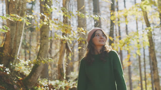 Woman in green sweater walking in forest in autumn