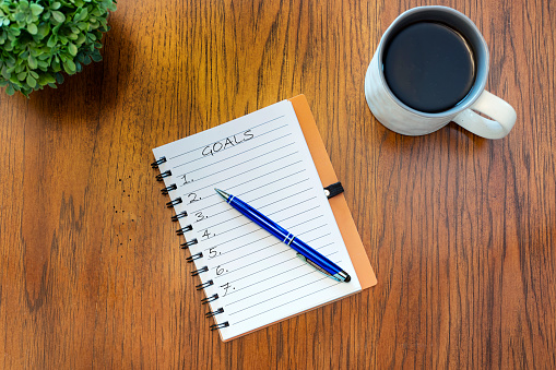 open notepad with pen with cup of coffee. Concept of goal setting or planning.