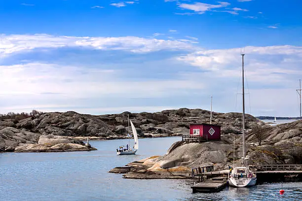 Sailingboat docked at small island with a red cottage in sweden