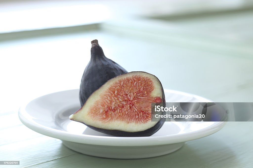 Fresh Sliced Fig A fresh fig halved on white china and aged wood, natural light. Mission Fig Stock Photo