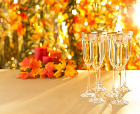Champagne glasses for reception in front of autumn background and candles