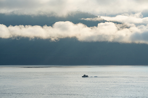 landscape of boat in Alaska sea with misty mountain as background