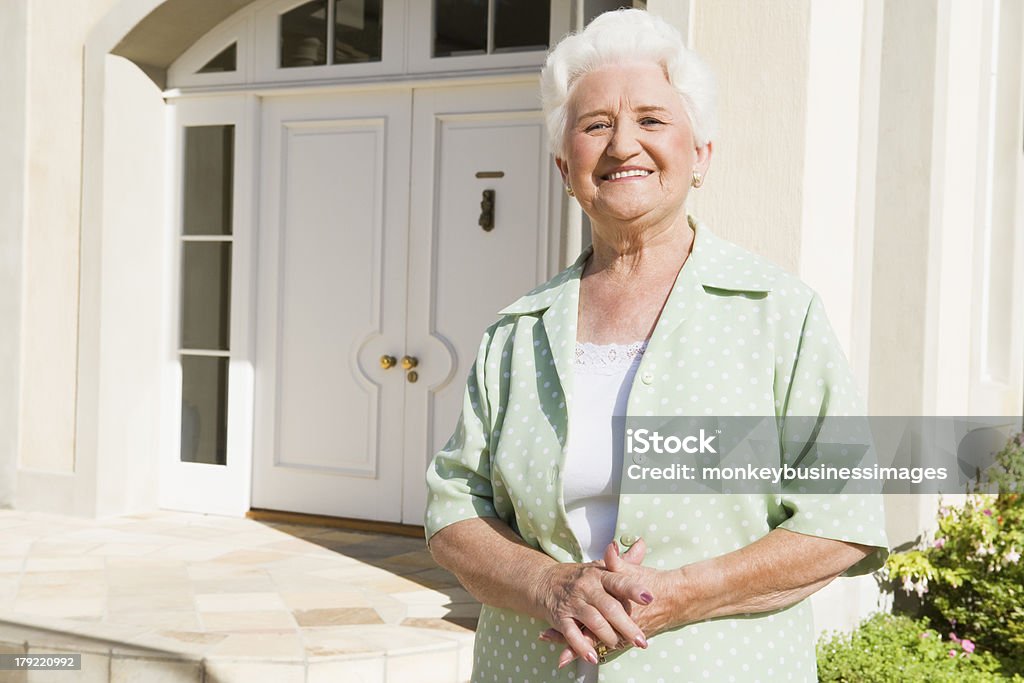 Senior donna in piedi fuori casa - Foto stock royalty-free di 70-79 anni