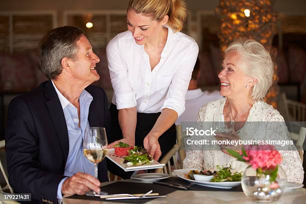 Waitress Serving Food To Senior Couple In Restaurant Stock Photo - Download Image Now