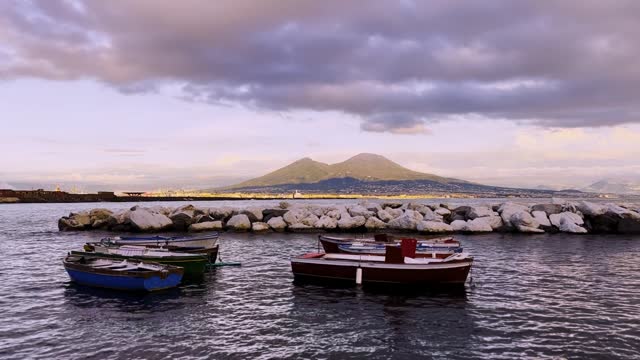Small Boats docked in Naples with a landscape view of Mount Vesuvius during Sunset
