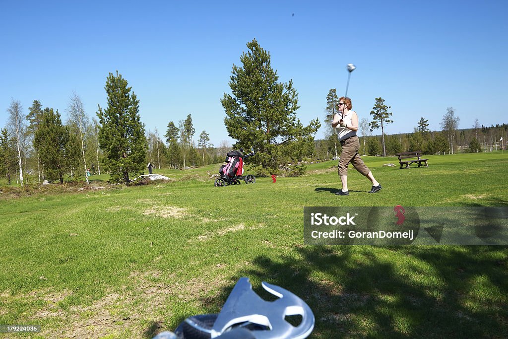 Lady swing Adult woman makes a golf swing on tea with her driver Adult Stock Photo