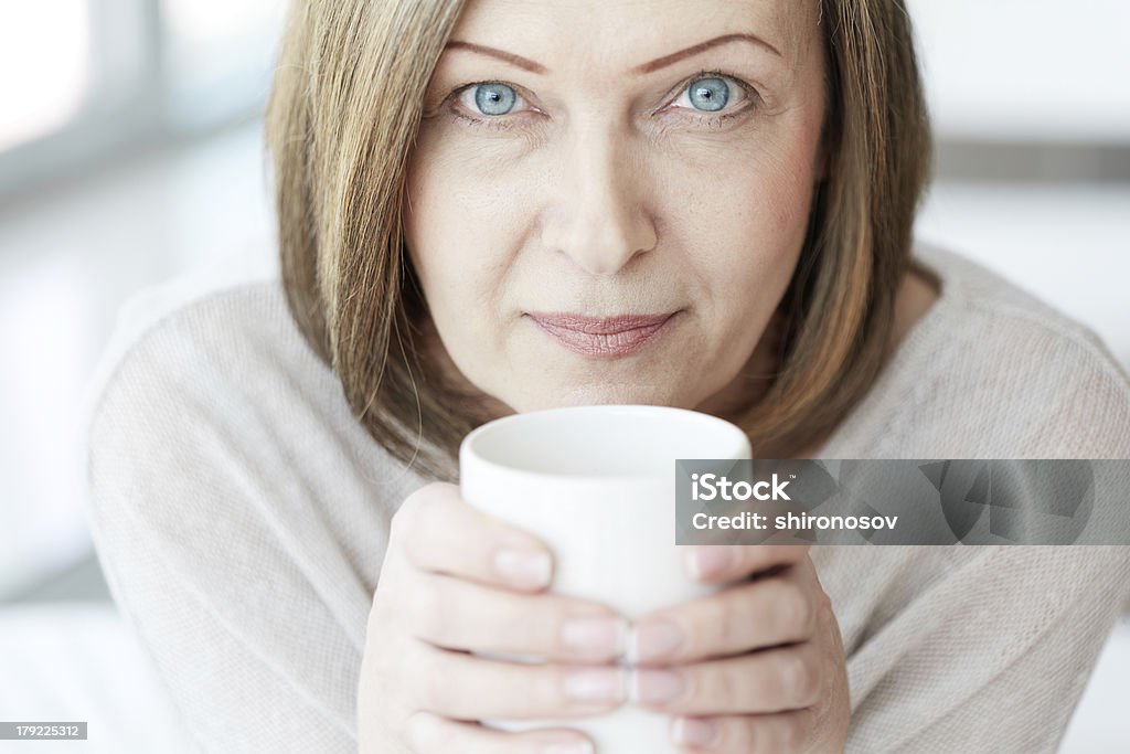 Mature woman Portrait of mature woman with cup looking at camera Active Seniors Stock Photo