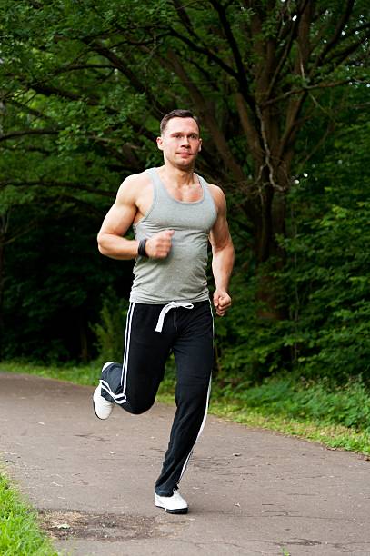 istock Man with black pants runs on road in park 179225695