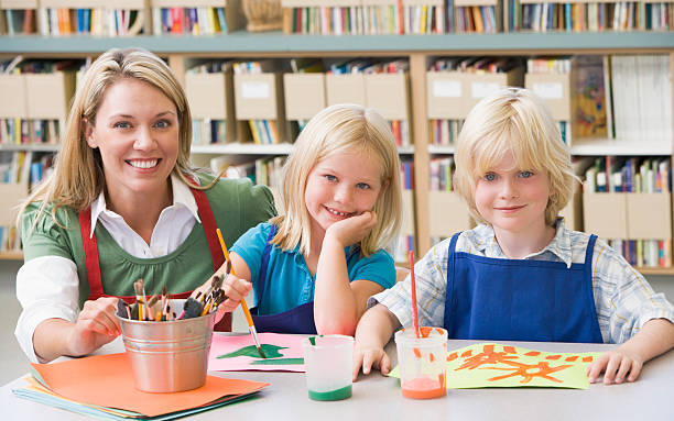 istock Kindergarten teacher sitting with students in art class 179226343