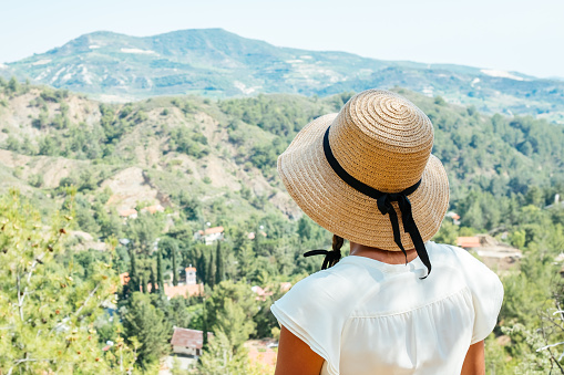 Beautiful woman wearing straw hat looking out towards valley view