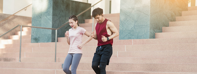 Asian young athlete man and woman in sportswear jogging exercise on the steps outdoor. Together young couple running outdoor in the morning. Healthy exercise concept.