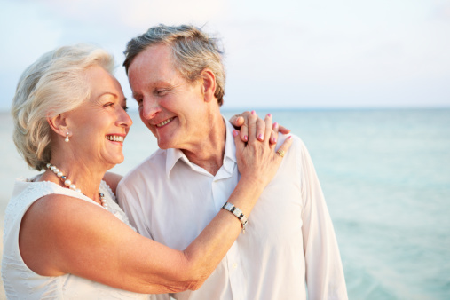 Senior Couple Getting Married In Beach Ceremony Smiling At Each Other