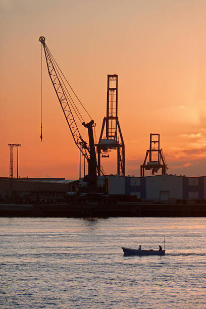 istock fishing boat in industrial harbor with cranes at sunset 179230482