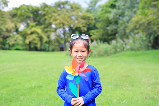Happy asian child girl with wind turbine in the garden