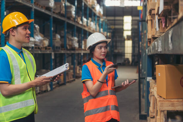 istock Warehouse management team check stock inventory. Asian men women worker use bar code scaner scan goods shelf writing checklist on clipboard. Teamwork logistics staff counting products store inventory 1792315305