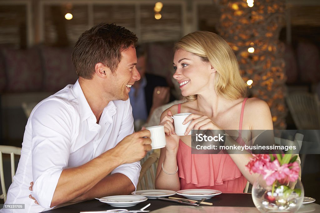 Couple Enjoying Cup Of Coffee In Restaurant Couple Enjoying Cup Of Coffee In Restaurant Sitting Down Looking At Each Other 20-29 Years Stock Photo