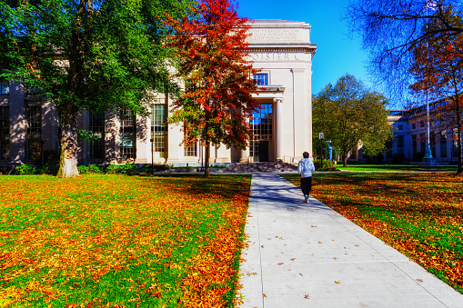 Cambridge, Massachusetts, USA - November 8, 2023: Student walking across Killian Court on an autumn afternoon. Massachusetts Institute of Technology (MIT) is a private reseach university founded in 1861. It has played a key role in the development of many aspects of modern science, engineering, mathematics, and technology, and is widely known for its innovation and academic strength.