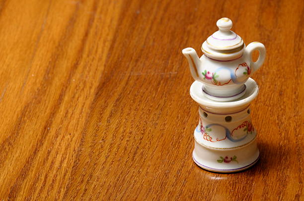 Dinette child : Miniature of tea port  on burning stove in porcelain on a wooden table