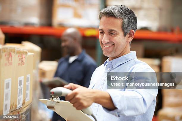 Man Holding A Clipboard And Scanning Packages In A Warehouse Stock Photo - Download Image Now