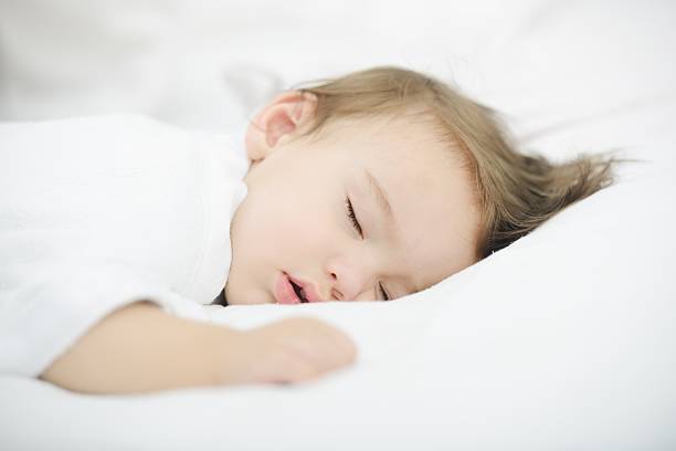 Baby sleeping on white bed with copy space stock photo