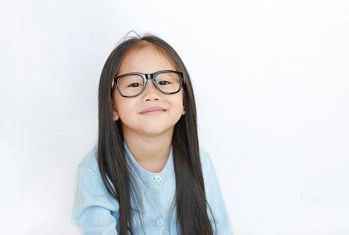 Portrait of little Asian kid girl wearing glasses against white background.