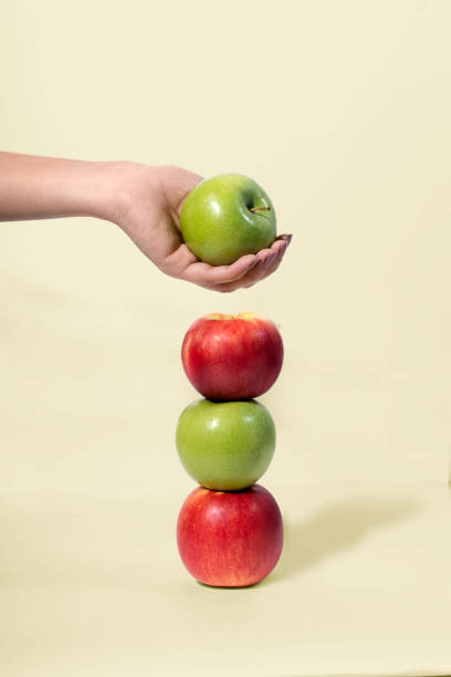 istock Red and green apples stacked and being picked up by hand 1792352628