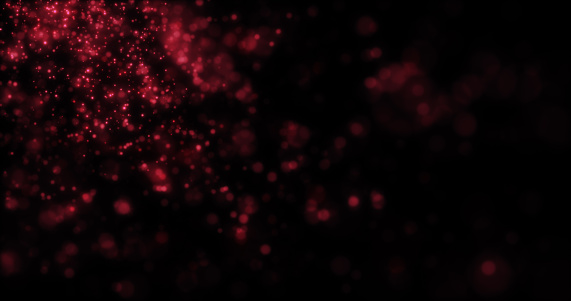 Blurred red abstract background of bokeh and small round particles of energy magical holiday flying dots on a black background.