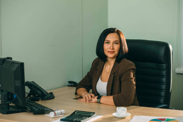 istock Young Happy Businesswoman Using Computer in Modern Office. Stylish Beautiful Manager Smiling, Working on Financial and Marketing Projects. Drinking Tea or Coffee from a Mug. 1792359414