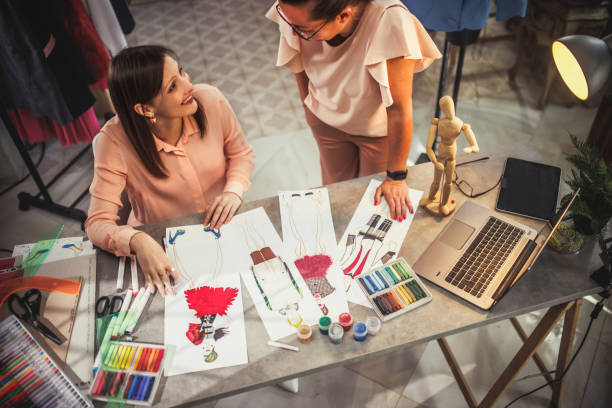 Fashion designer looking at sketch on working table in workshop
