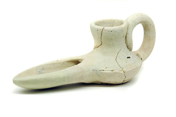 Close view of an ancient islamic oil lamp artifact on white background.