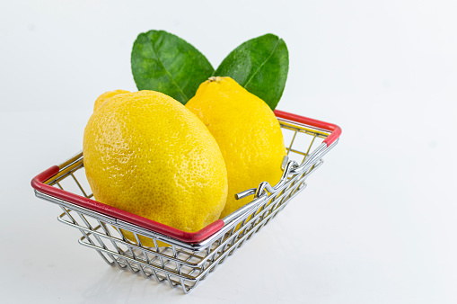 Bright yellow lemons in a basket with sour taste on white background.