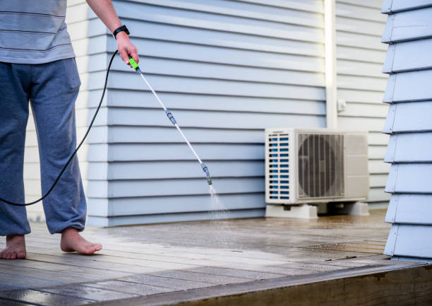 istock Man cleaning wooden deck with hand-held pressure sprayer, preparing deck before staining. 1792441400