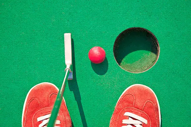 Close-up of miniature golf hole with bat and ball