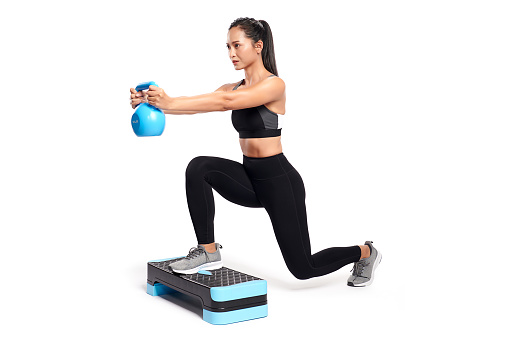 an asian woman is working out with kettlebell wearing the sport exercise suit with white background,