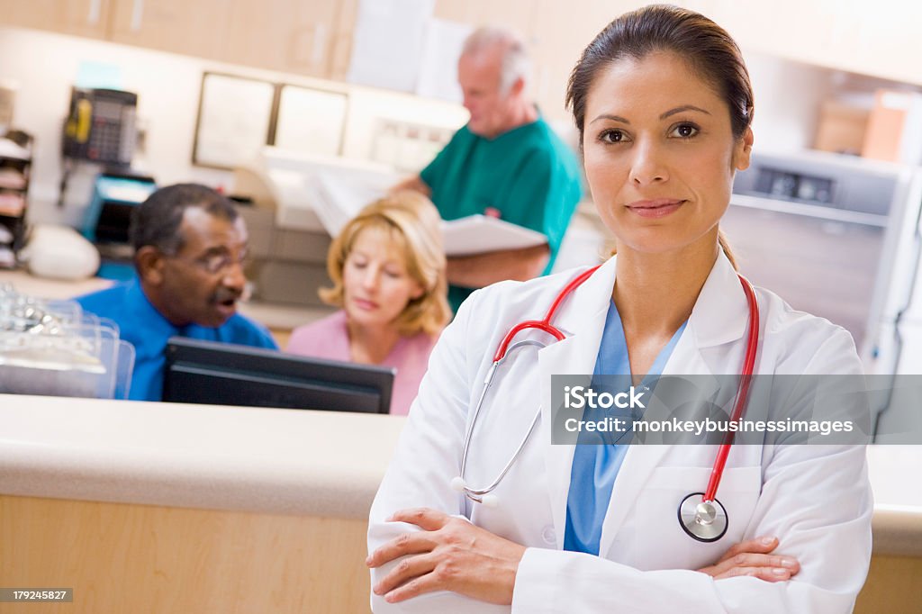Some doctors and nurses at the reception area of a hospital  Doctors And Nurses At The Reception Area Of A Hospital Having A Conversation In The Background Latin American and Hispanic Ethnicity Stock Photo