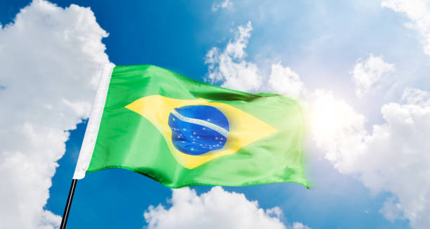 istock Brazilian flag waving against blue sky background 1792459203