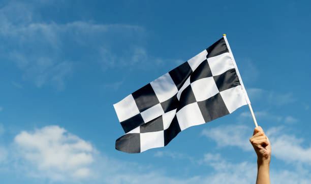 istock Checkered race flag in hand against blue sky 1792462451