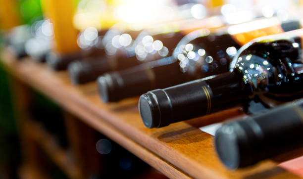 Group of red wine bottles on wooden racks in a row stock photo
