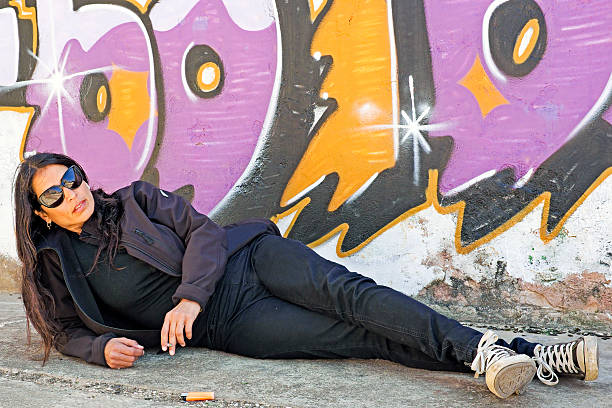 istock Smoking woman in black at the graffiti brick wall 179247091