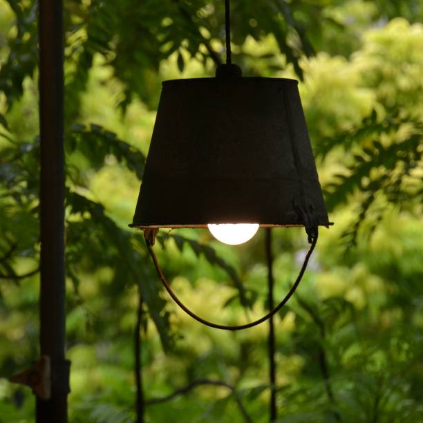istock Old vintage rusty metal bucket or pail is hung upside down and turned into a rustic light fitting outside on a tropical deck in the rain forest 1792477548
