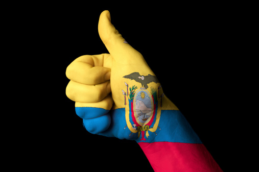 Hand with thumb up gesture in colored ecuador national flag as symbol of excellence, achievement, good, - for tourism and touristic advertising, positive political, cultural, social management of country