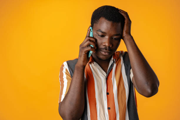 istock Upset stressed african man talking on the phone against yellow background 1792496170