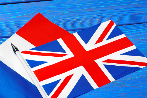 Flags of France and Great Britain on blue wooden background close up