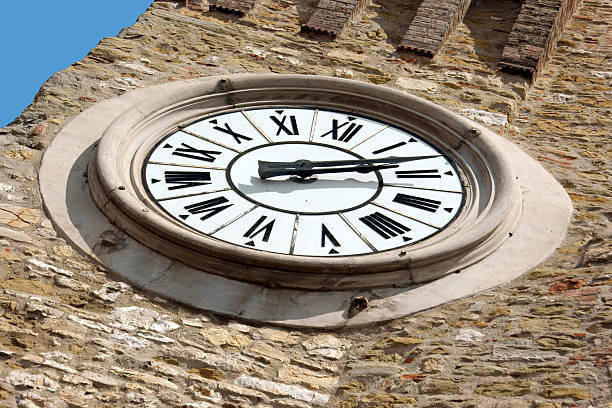 Ancient clock on the stone belltower of the Temple of Minerva, iconic landmark in Assisi, Italy