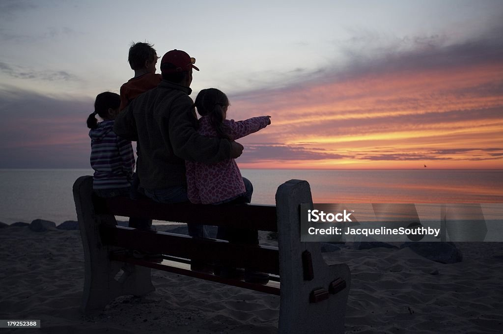 Famille sur un banc en admirant le coucher de soleil - Photo de Michigan libre de droits
