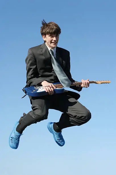 young happy businessman with guitar jumping high