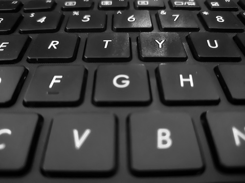 A row of alphabets on a laptop keyboard in the background