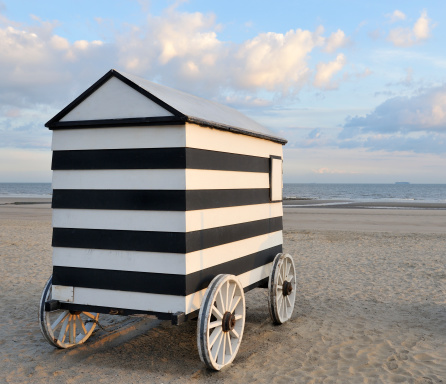Old wheeled bathing hut on empty sandy beach with horizon and sea in background.For similar images please see the lightbox:
