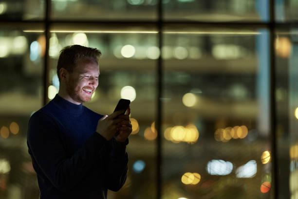istock Happy man text messaging on cell phone indoors at night. 1792550911