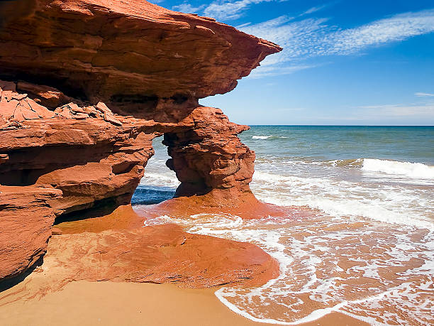 Sea Arch on PEI Coast, Canada Waves break near a sea arch of crumbling red sandstone on the Seaview Coast of Prince Edward Island, Canada. The Atlantic's Gulf of St. Lawrence lies beyond. gulf of st lawrence photos stock pictures, royalty-free photos & images